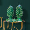 Two green ceramic artichoke ornaments on a gold table