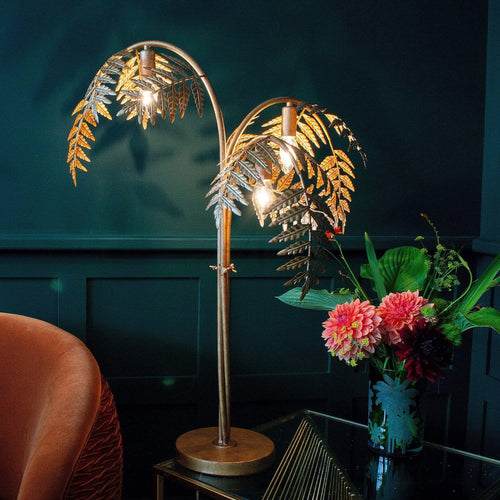 A palm leaf lamp on a table next to a flower vase