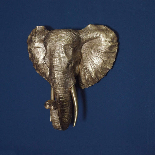 A gold elephant head mounted on a blue wall