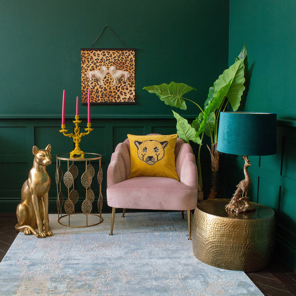 A room with green walls, a gold side table, an armchair, and elegant decor