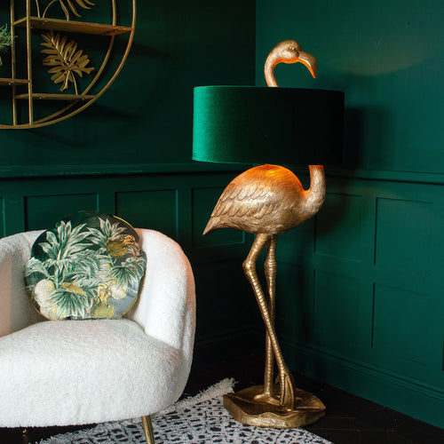A gold flamingo floor lamp with green shade, next to a white armchair