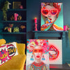 A yellow couch with cushions, multiple LED neon canvas artworks, and various decorative items