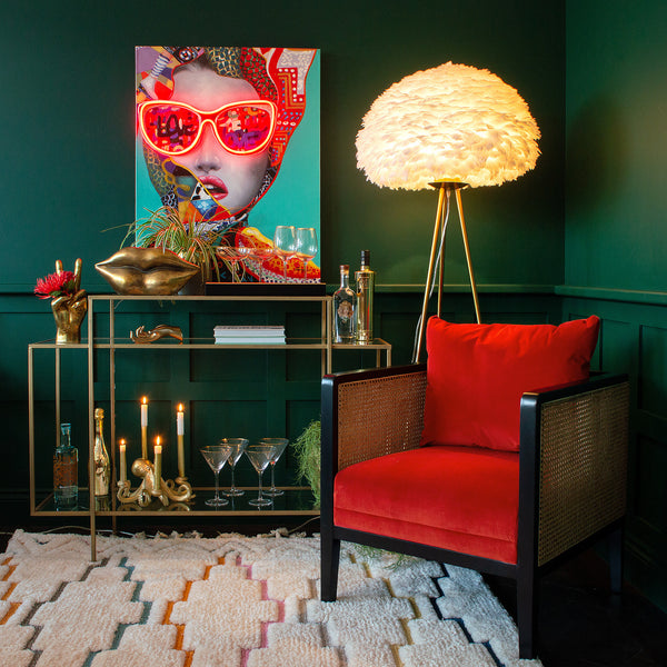 A red chair, a console table with various decorative items, a lamp, an LED neon canvas artwork, and a rug