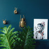 A wall with a portrait of a woman and gold beetle wall decor