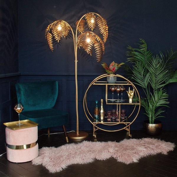 A chair and a palm tree lamp, next to a round drinks trolley