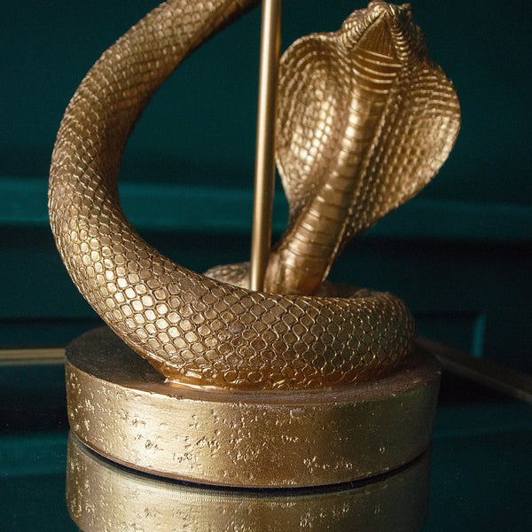 A close-up of a golden snake coiled around a lamp with a round base