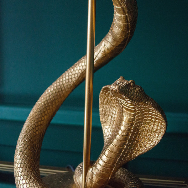 A golden snake coiled around a lamp with a matching gold base