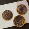Three leopard print coasters with a glass placed on top of one of them