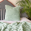 A cosy bed with a mint green cushion and matching blanket