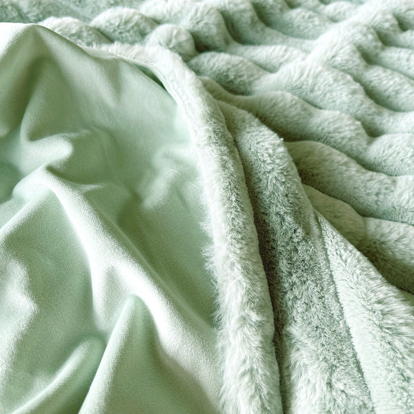 Close-up of a mint green faux fur throw with a striped pattern