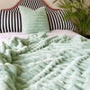 A bed with a mint green faux fur throw and pillows