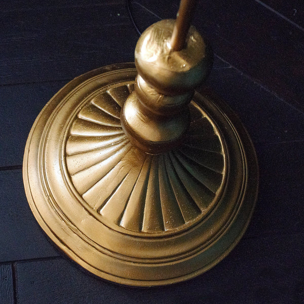 Close-up of the round base of a golden parrot floor lamp