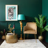 A room featuring a chair, a parrot floor lamp, a framed leopard print, a rug, plant pots, and decorative items