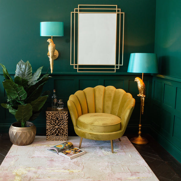 A room featuring a yellow armchair, a parrot floor lamp, a wall mirror, a plant pot, a side table, and a rug