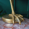 A golden bird's leg lamp resting on a marble table