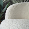 A close-up of a white armchair with sheepskin upholstered seat