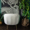 Back view of a white armchair in front of a large wall hanging print and plants