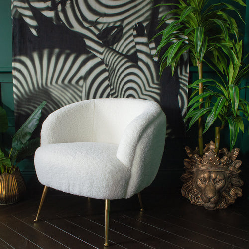 A white armchair in front of a large abstract print on a wall and plants on both sides